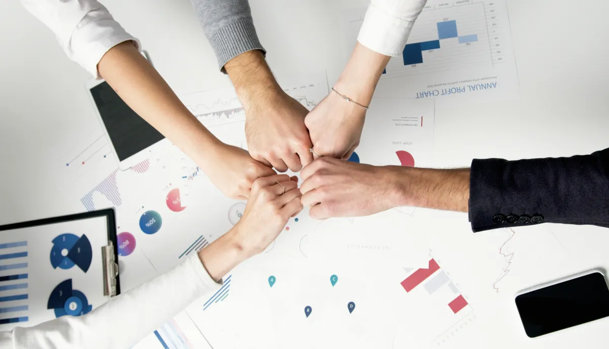 Team members pointing to graphs and notes on a table, illustrating AP360 Marketing’s hands-on strategies that small businesses and start-ups value.