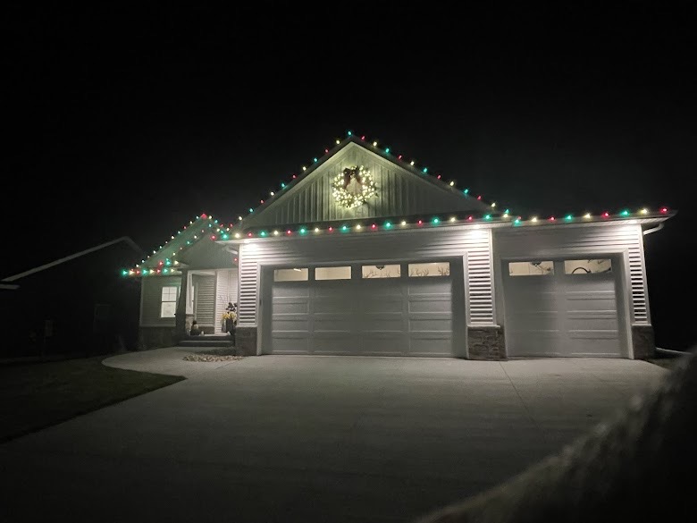 Home decorated with red and green C9 LED Christmas lights along the roofline and garage for holiday installation.