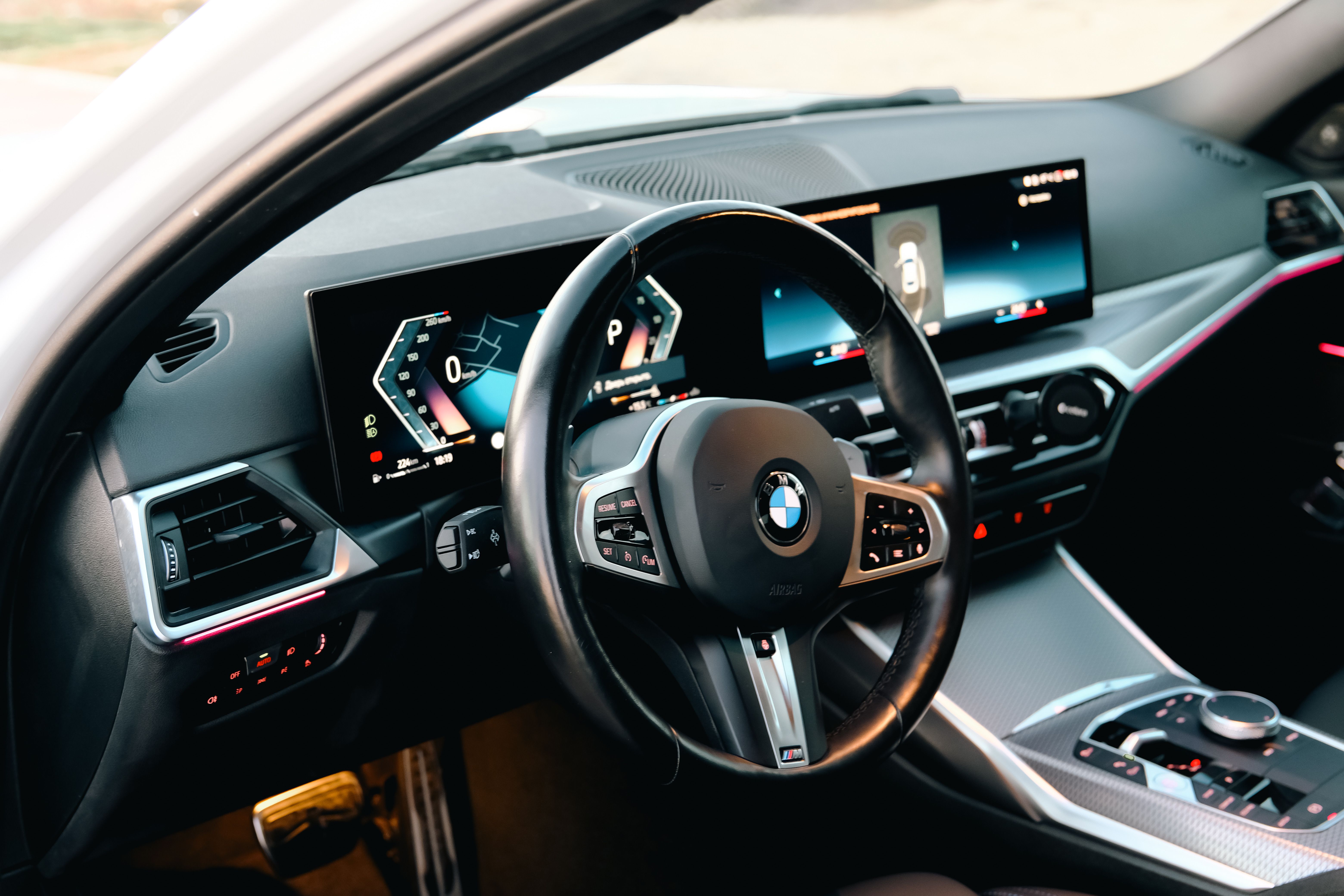 Circular cropped photograph showing a person's hands gripping a car steering wheel