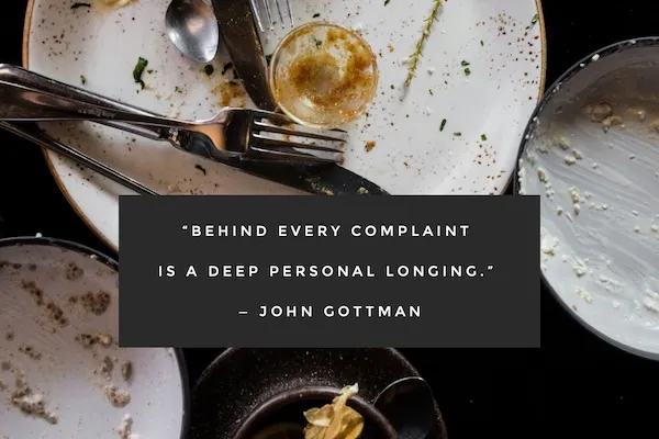 Close-up of dirty dinner plates and utensils after a meal, symbolizing relationship conflict and emotional disconnect, with the quote: “Behind every complaint is a deep personal longing.” — John Gottman