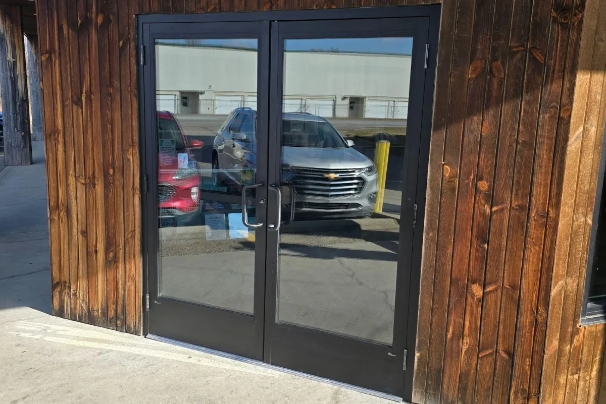 ADA-compliant commercial glass entry doors installed on a wood-paneled building by RDB Glass in Dayton, OH.