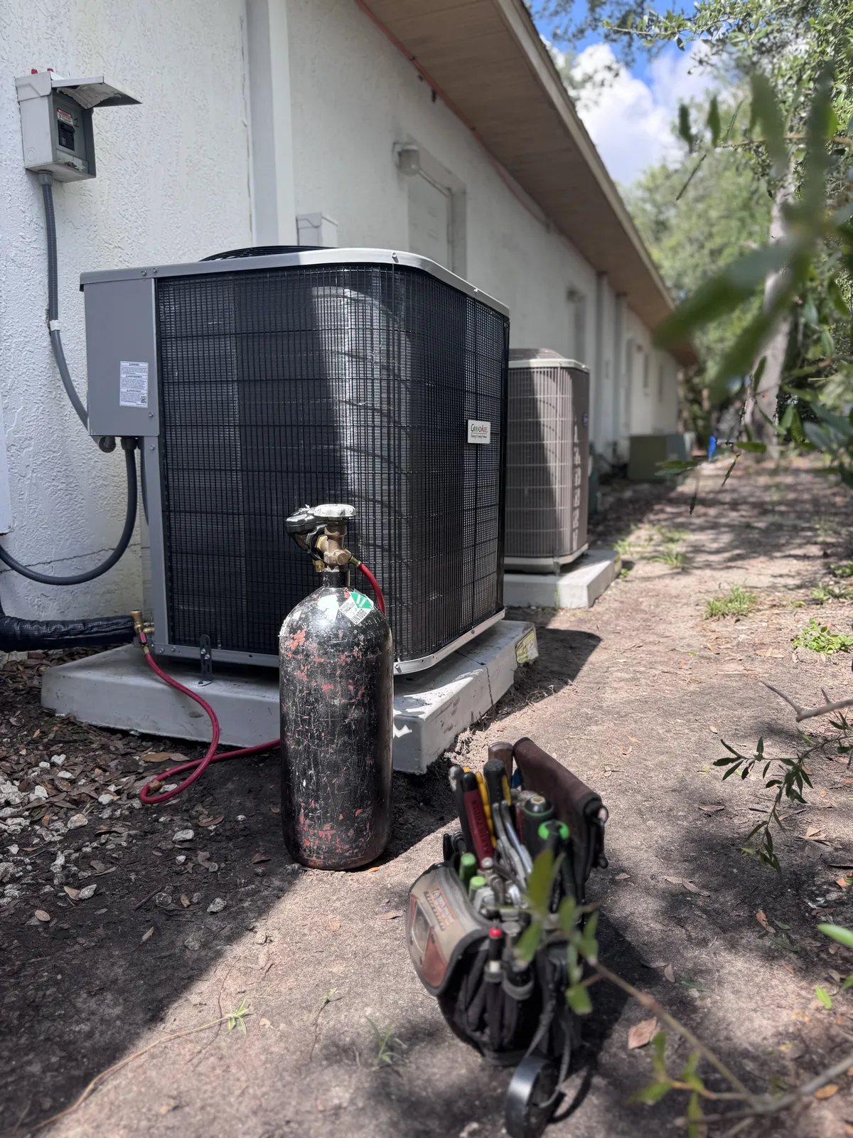 AC unit outdoors with maintenance equipment ready for energy-saving inspection and service.