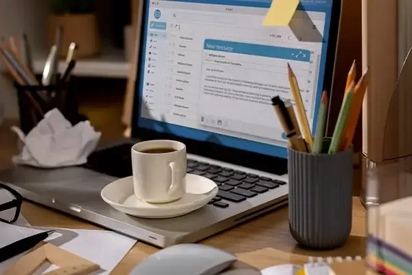A laptop placed on a desk next to a coffee cup, suggesting a workspace setting.
