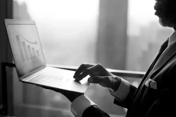 Black and white photo of a businessman focused on his laptop, showcasing a professional work environment.
