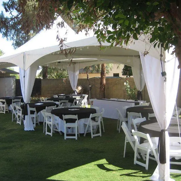 20x20 high peak frame tent at a backyard celebration in warm sunset light with elegant decor and guests mingling.