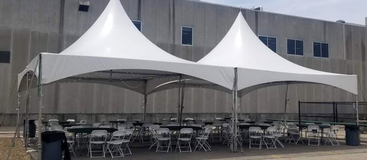 A 20x20 tent hosting a community festival, with a live band performing on a small stage, colorful banners, and a diverse crowd enjoying the festivities under the tent.