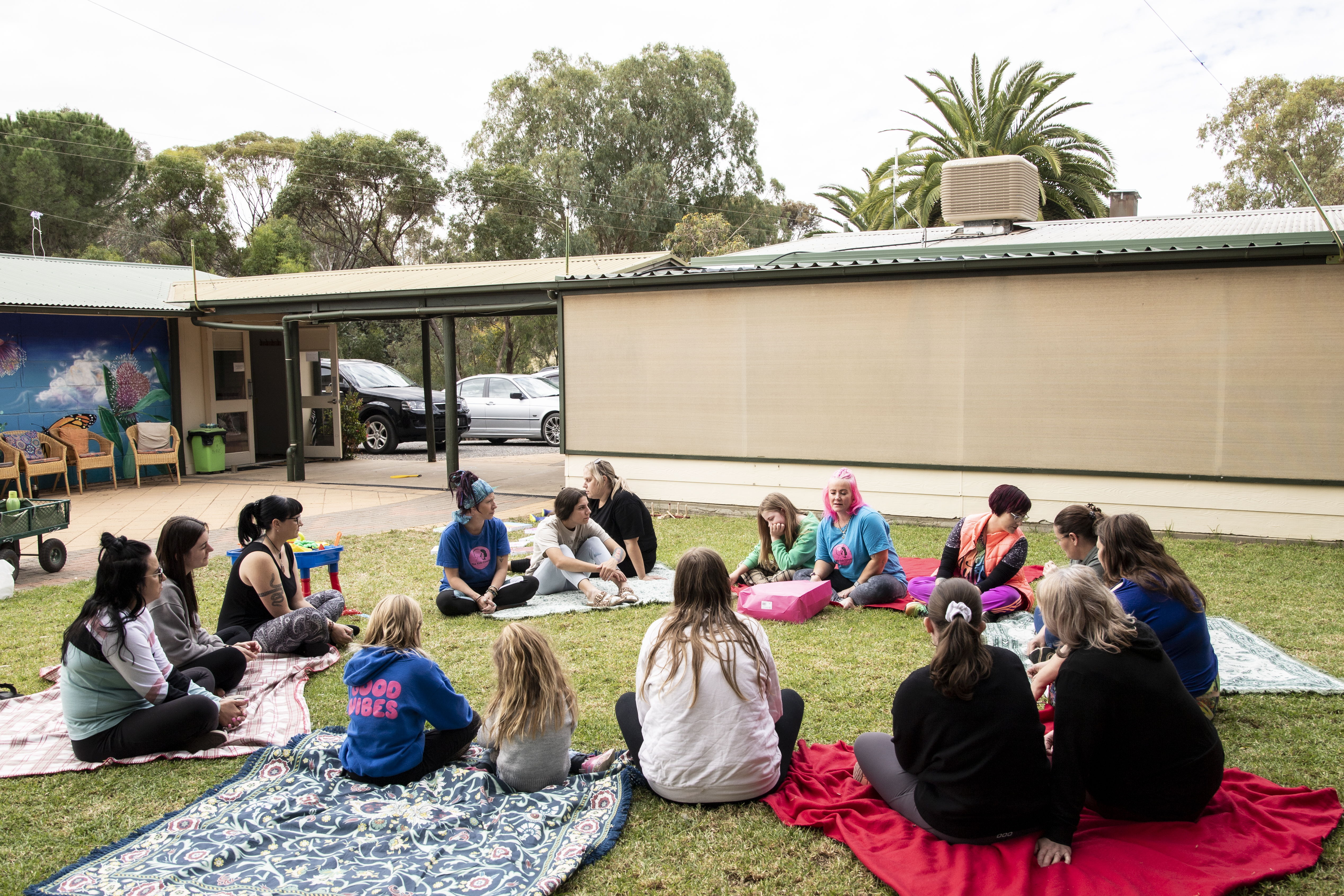 A young participant in a wheelchair, surrounded by family members of different ages and backgrounds, in a vibrant outdoor park setting. Everyone is smiling and engaged, radiating inclusion and joy.