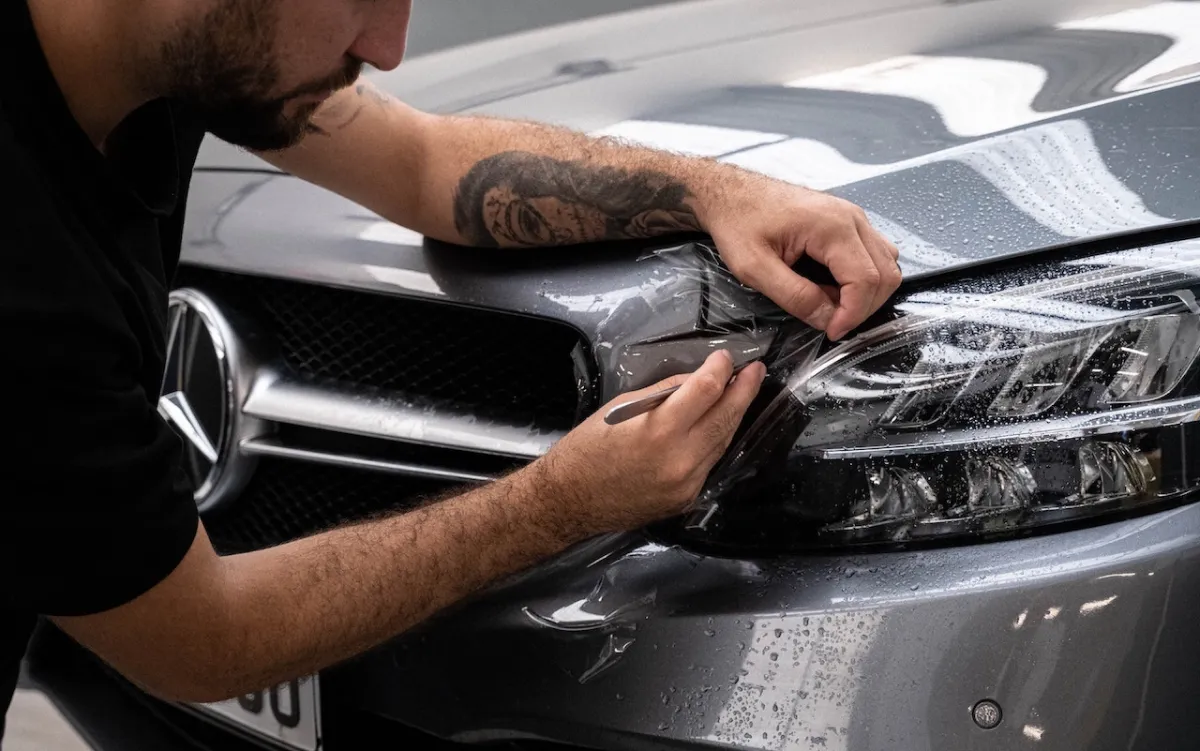 A man applying Paint Protection Film (PPF) to a car surface