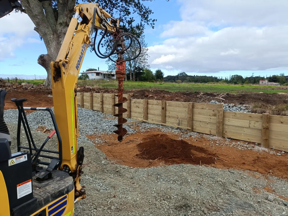 Auger drilling post holes ahead of timber retaining wall construction in Whangarei
