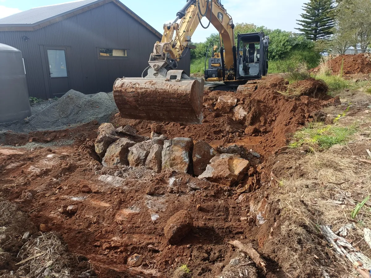 Excavator claw removing stump during landscape earth shaping Northland