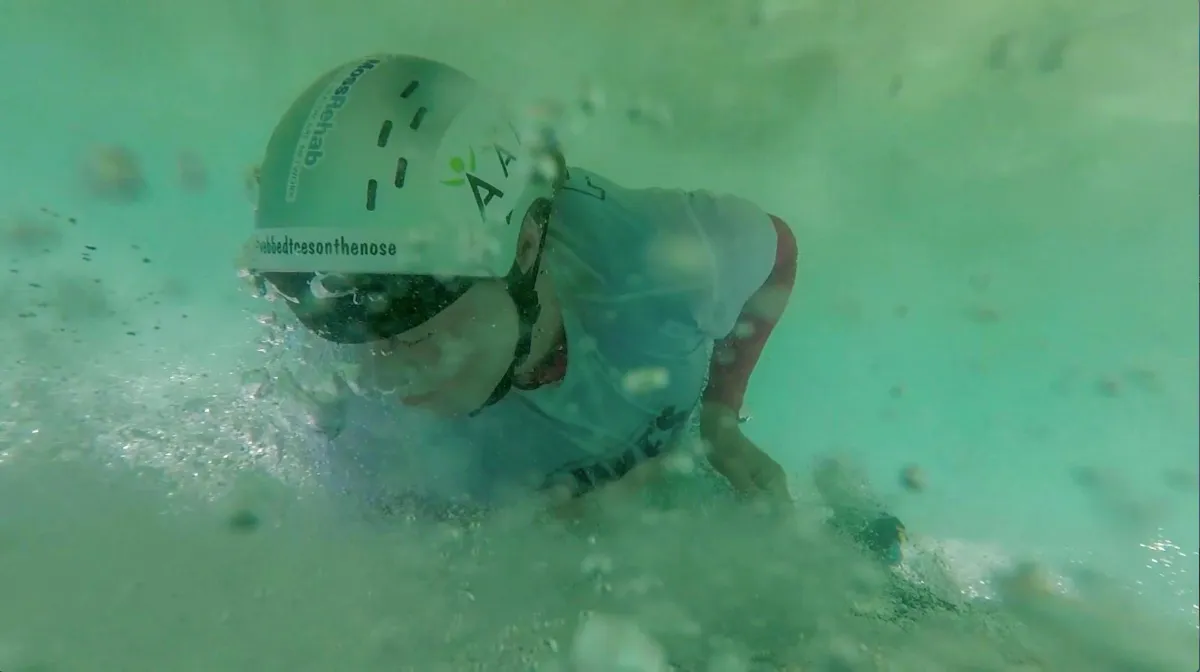 person underneath a surfboard in pale green water there are lots of bubbles but she looks serene