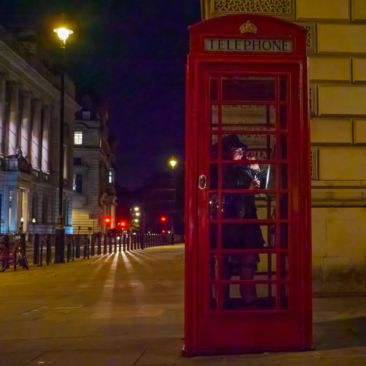 woman in london red telephone box at night