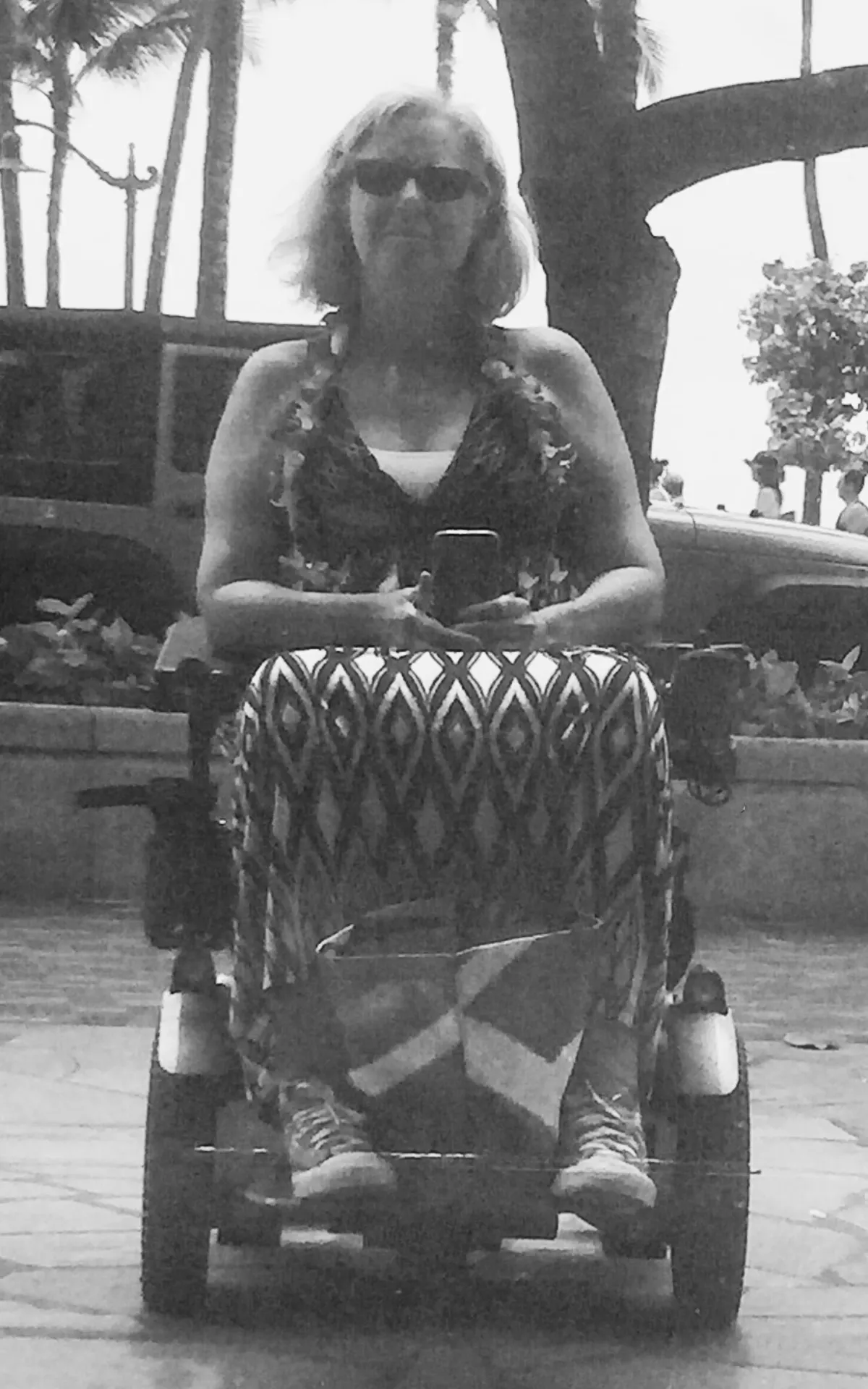 reflection of woman sitting on wheelchair in a maxi dress with a flower lei around her neck