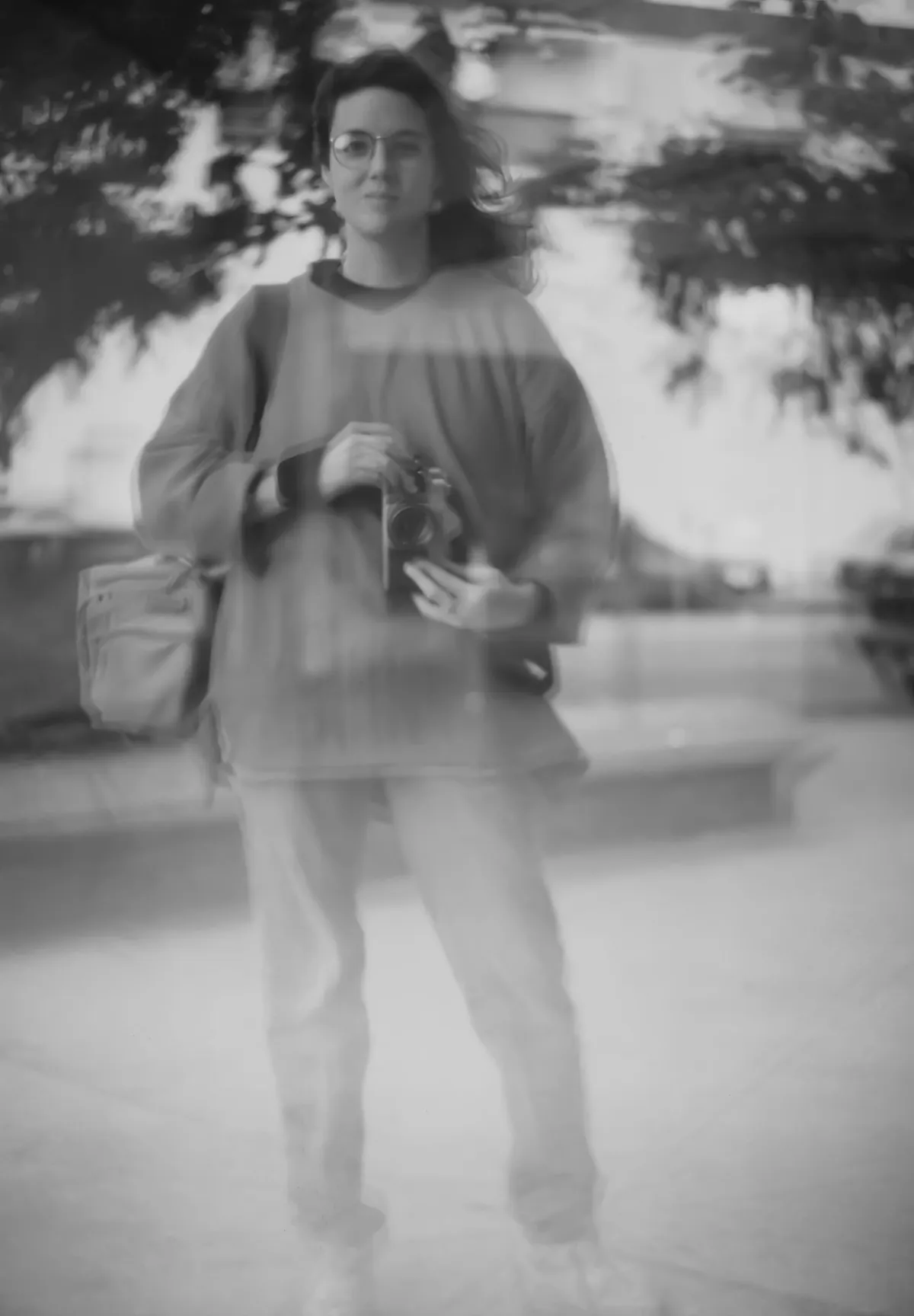 black and white reflection of young woman standing and holding a camera