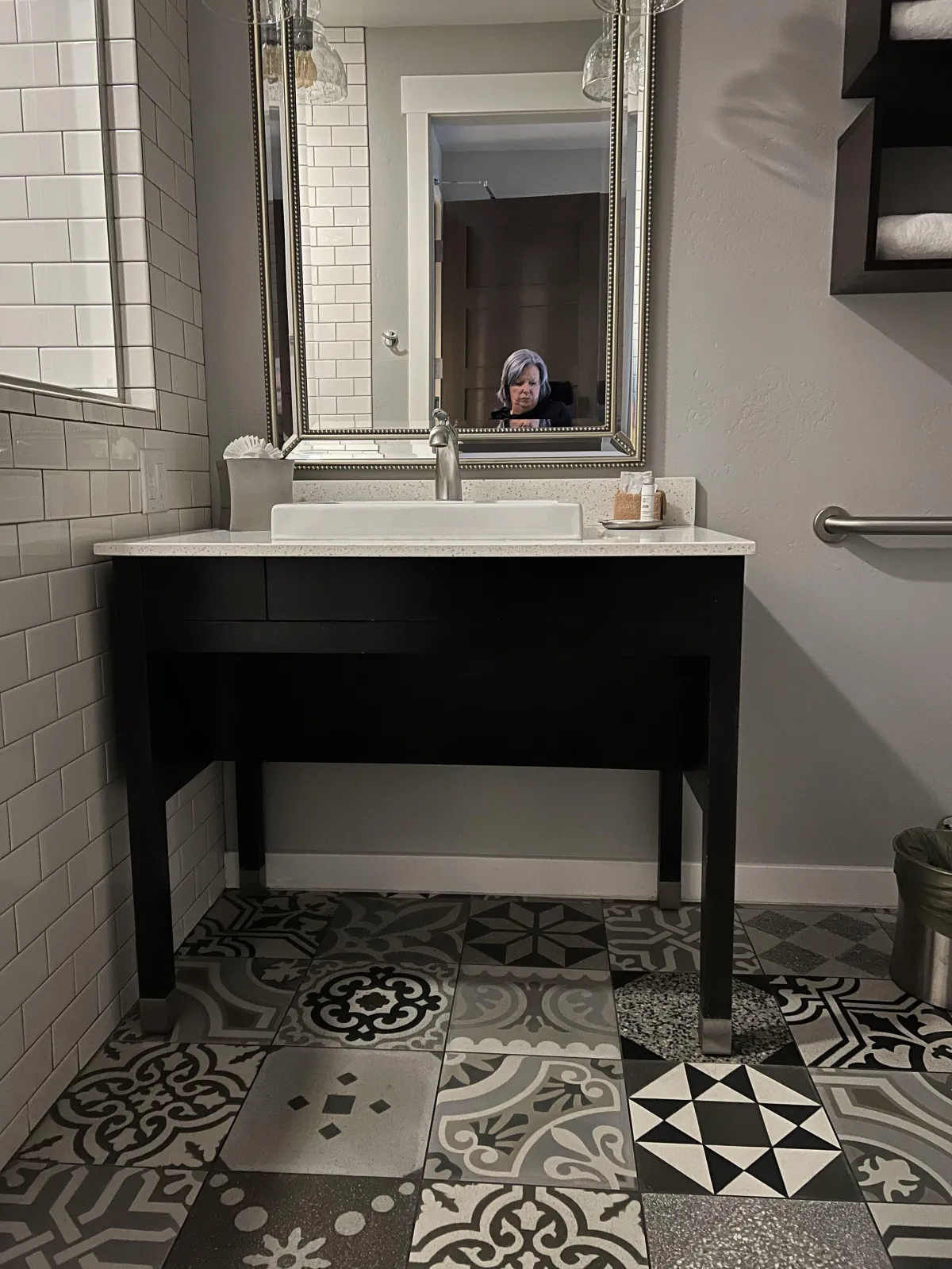 multi-mosaic floor tile and pull under sink vanity in hotel room bathroom