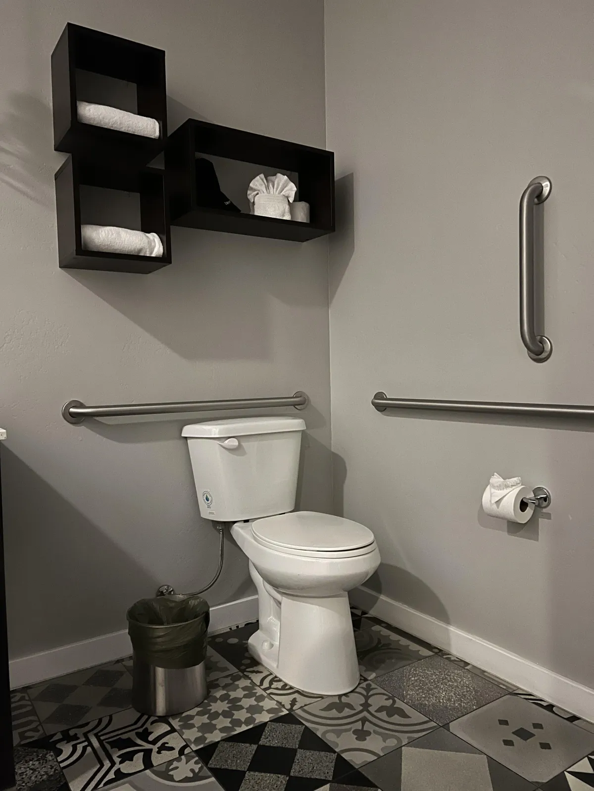 toile with grab bar, decorative boxes holding spare towels above the toilet