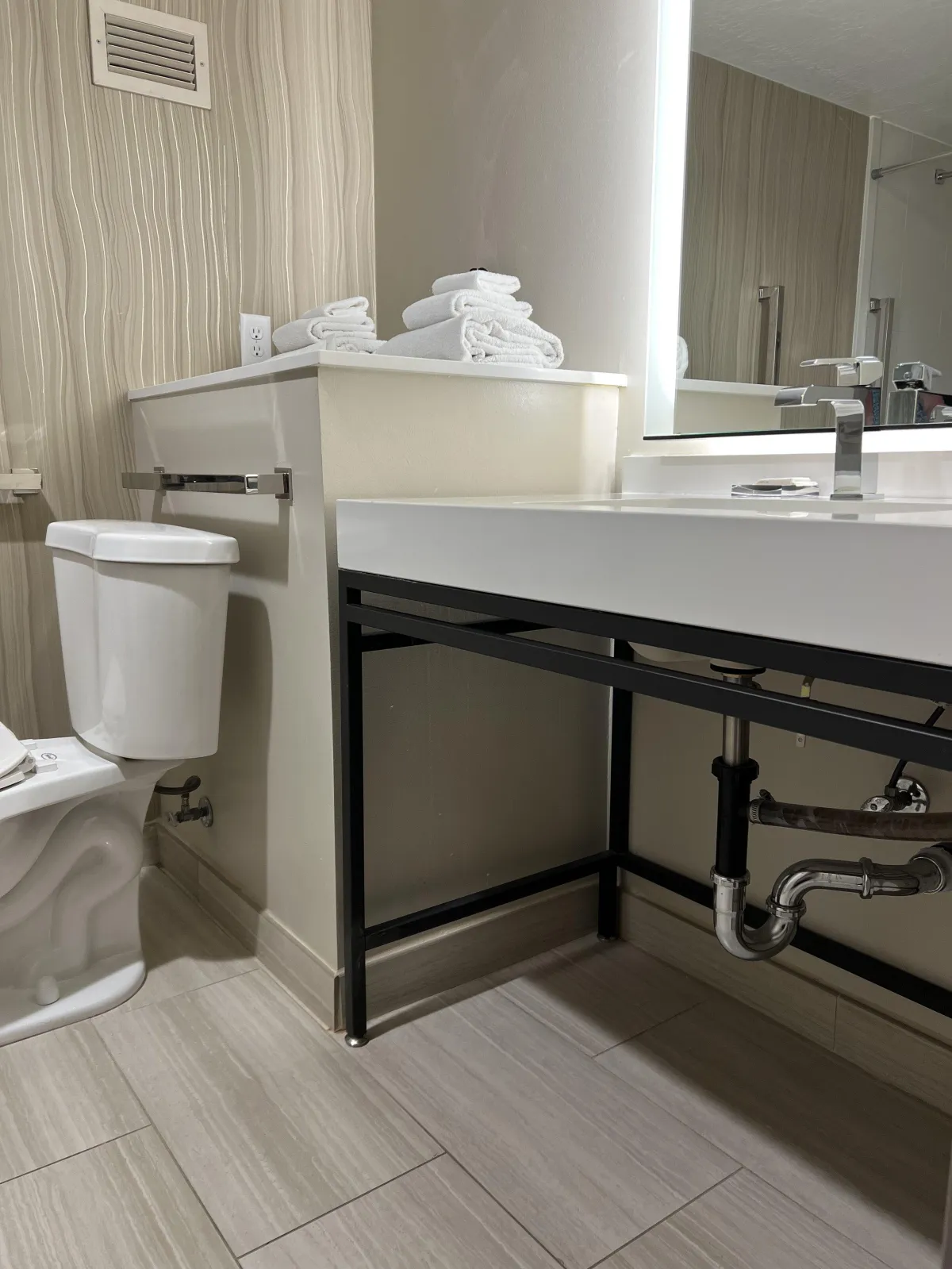 hotel bathroom with toilet and sink with exposed pipes