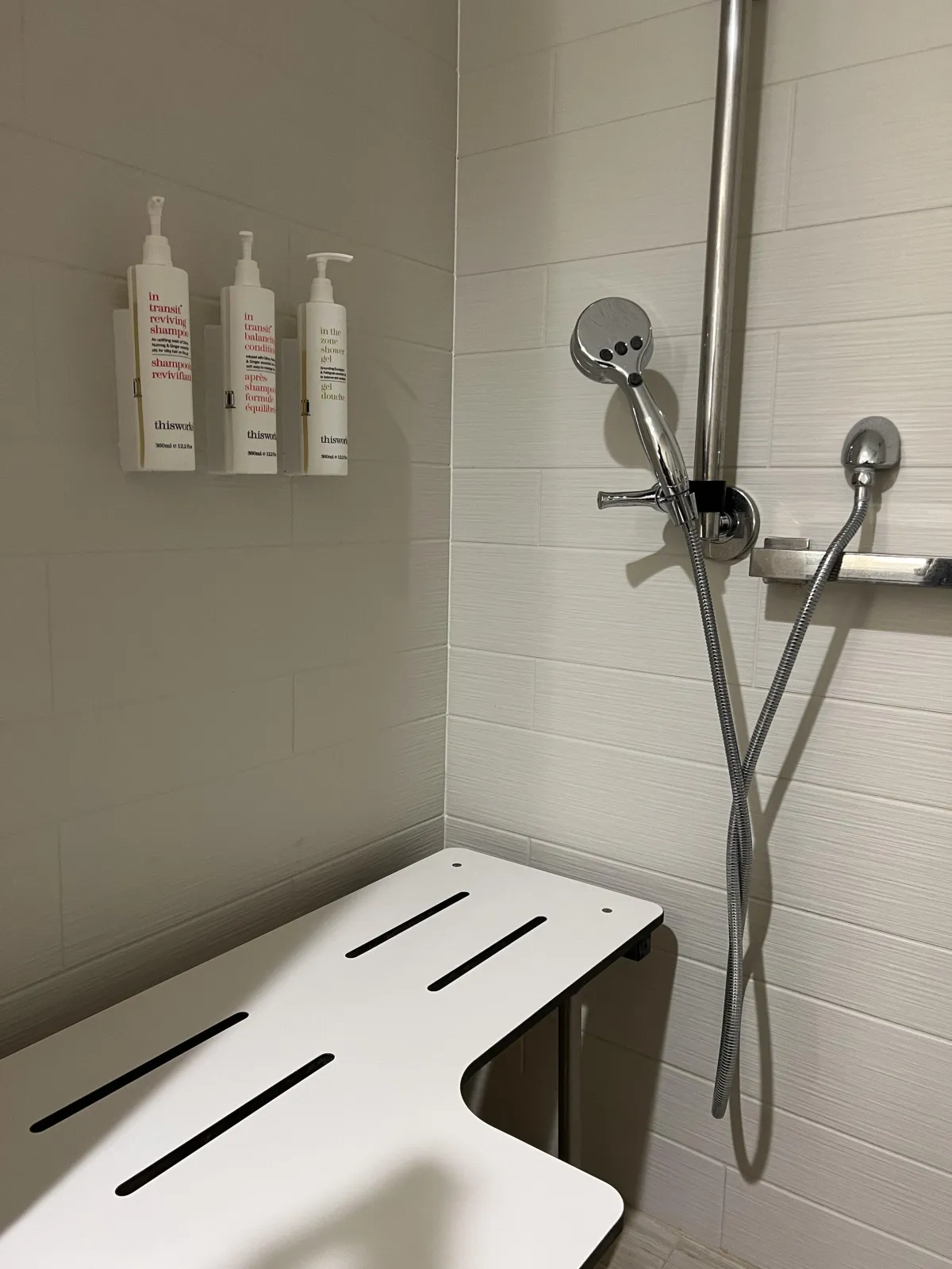 shower in hotel with soap dispensers mounted above the bench seat