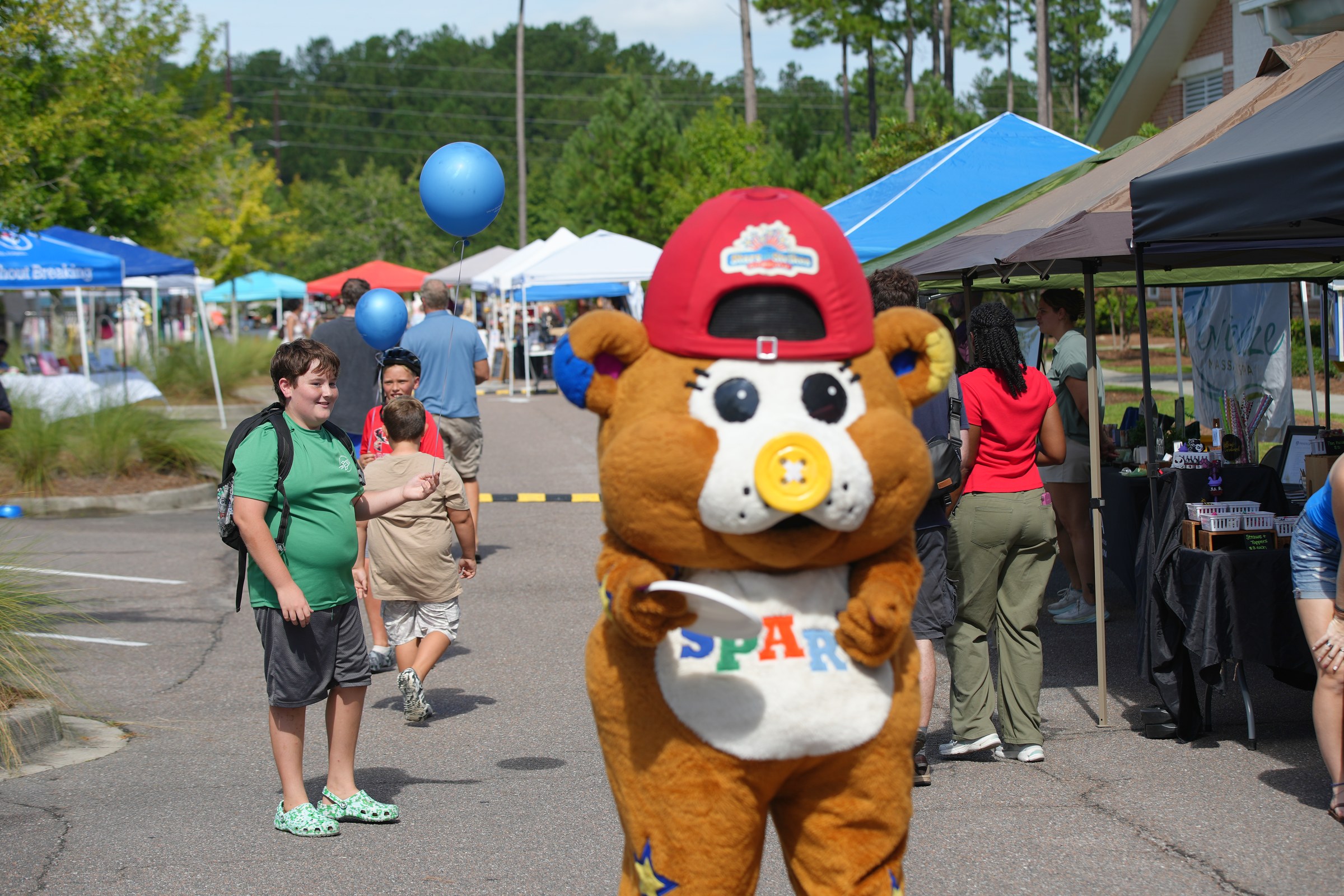 Costumed mascot greeting kids and families at the 2026 market