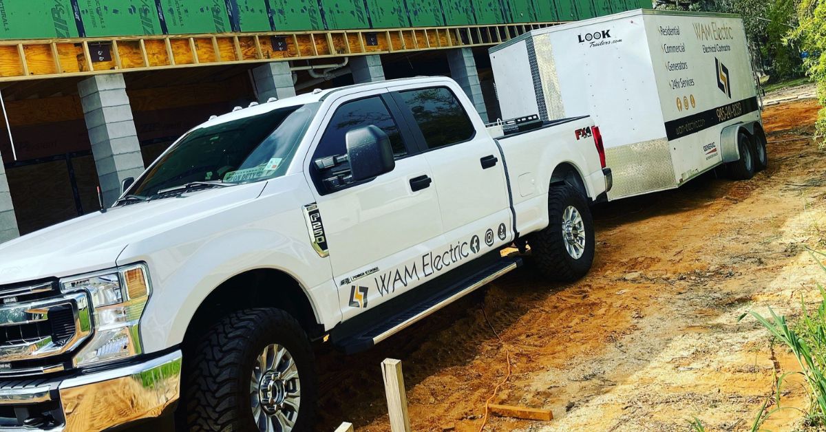 WAM Electric service truck and trailer parked at a whole-house electrical rewire project site in Louisiana.