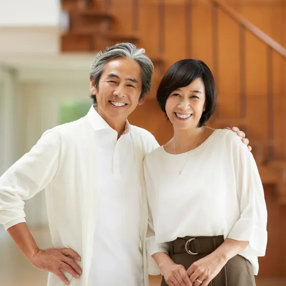 Elderly couple embracing warmly, both smiling with happiness and looking at the camera.