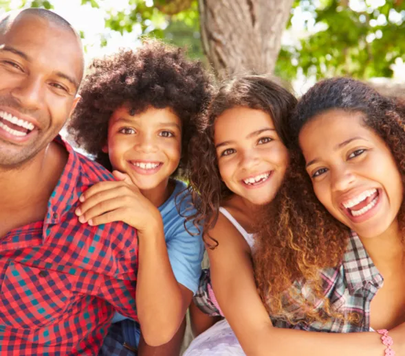 Smiling multi-generational family gathered together, radiating warmth and happiness in a cozy indoor setting.