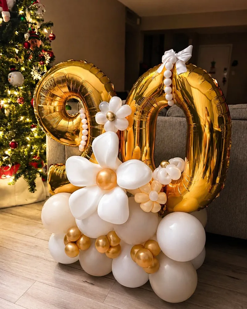 Arreglo de cumpleaños con globos dorados del número 90 y flores blancas