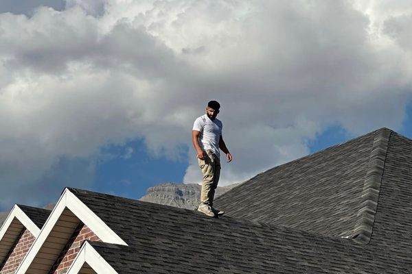 Roofing specialist performing a detailed roof inspection on a residential home in Utah