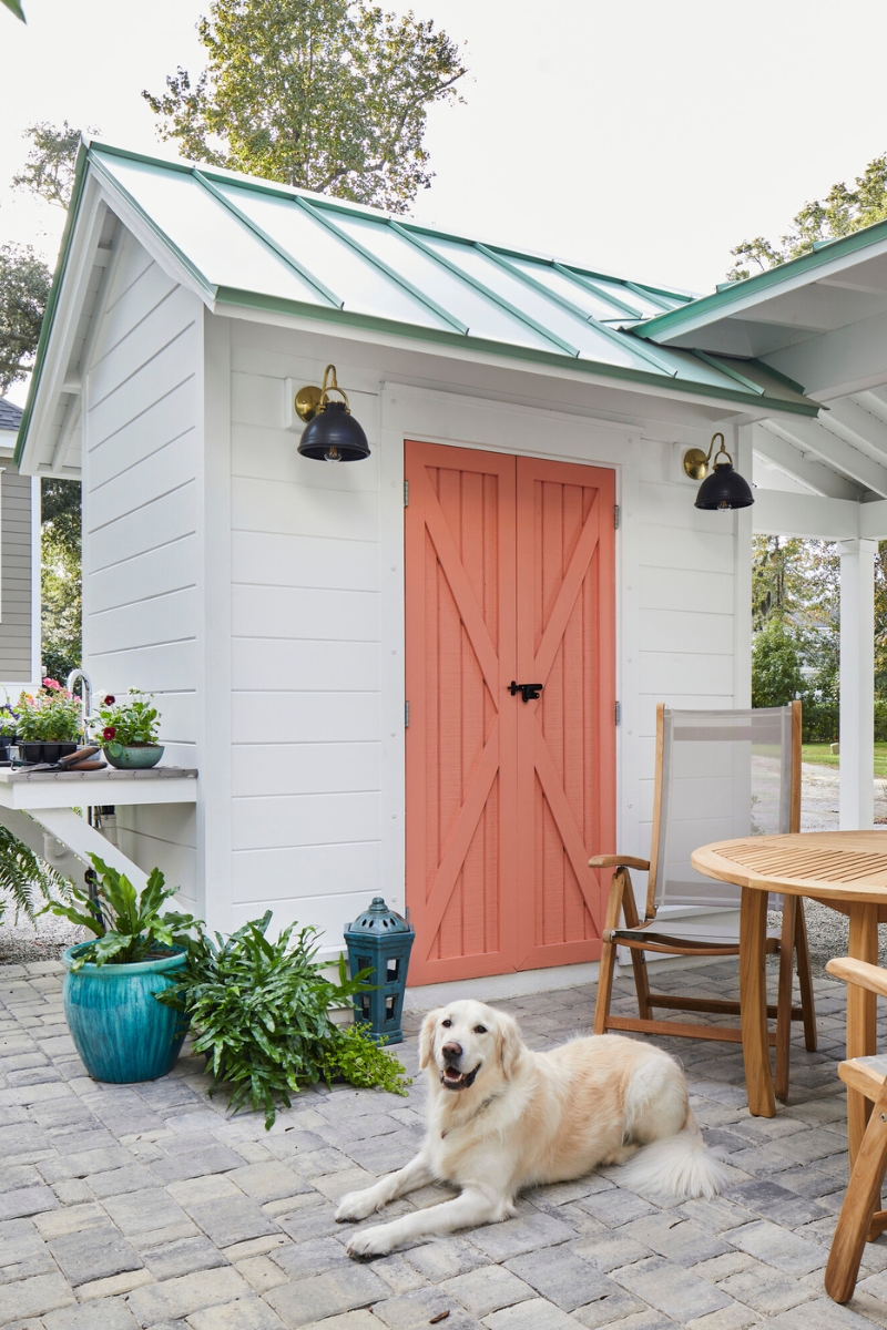 Custom exterior wall lighting installed on white Utah home with metal roof and decorative barn-style door