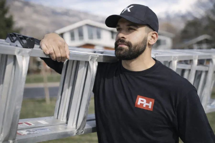 Yasir, Owner and CEO of PowerHouse Roofing, holding ladder and representing premium exterior craftsmanship in Utah