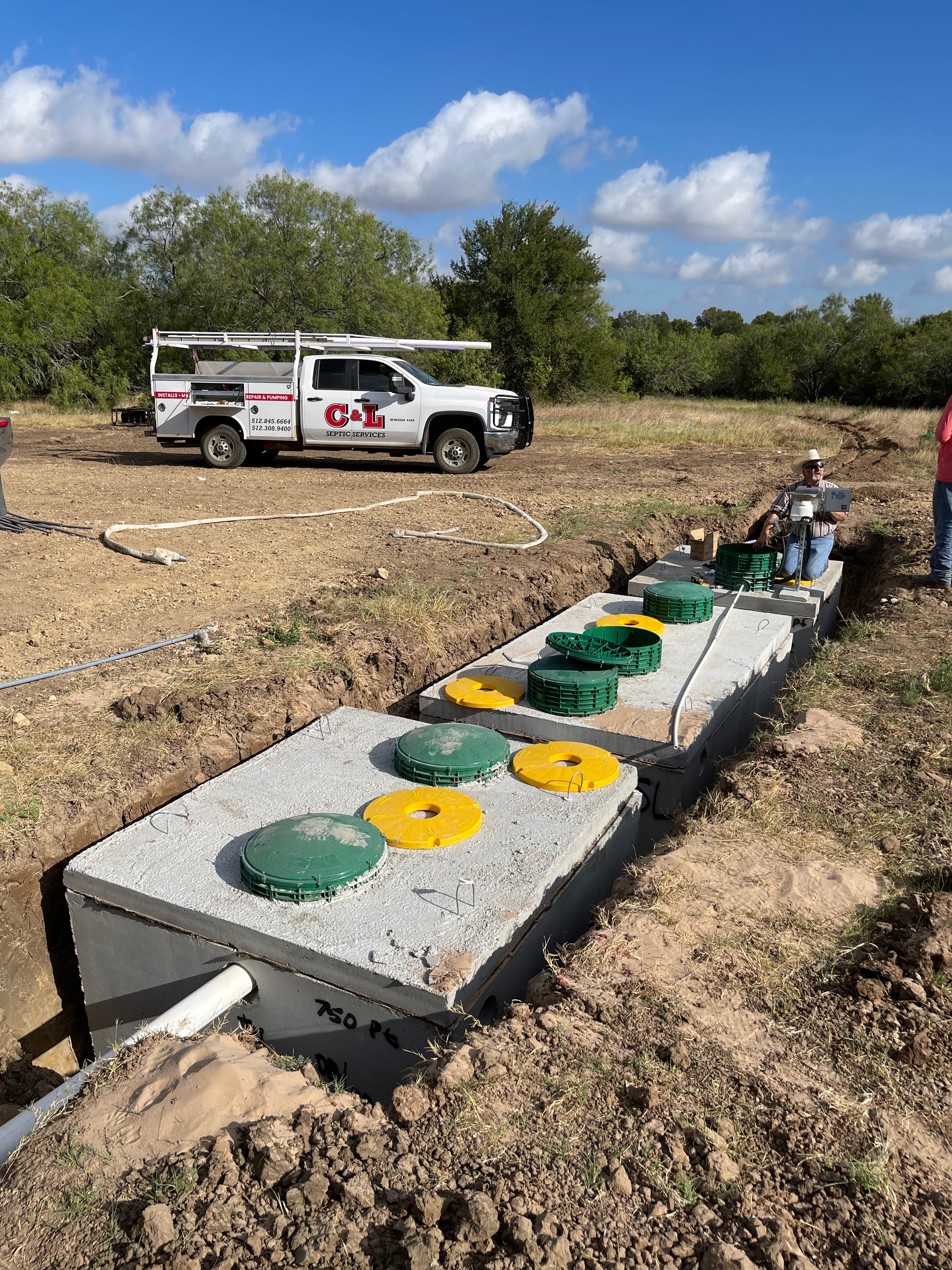 Excavator lifting concrete tank during excavation in Bastrop Texas
