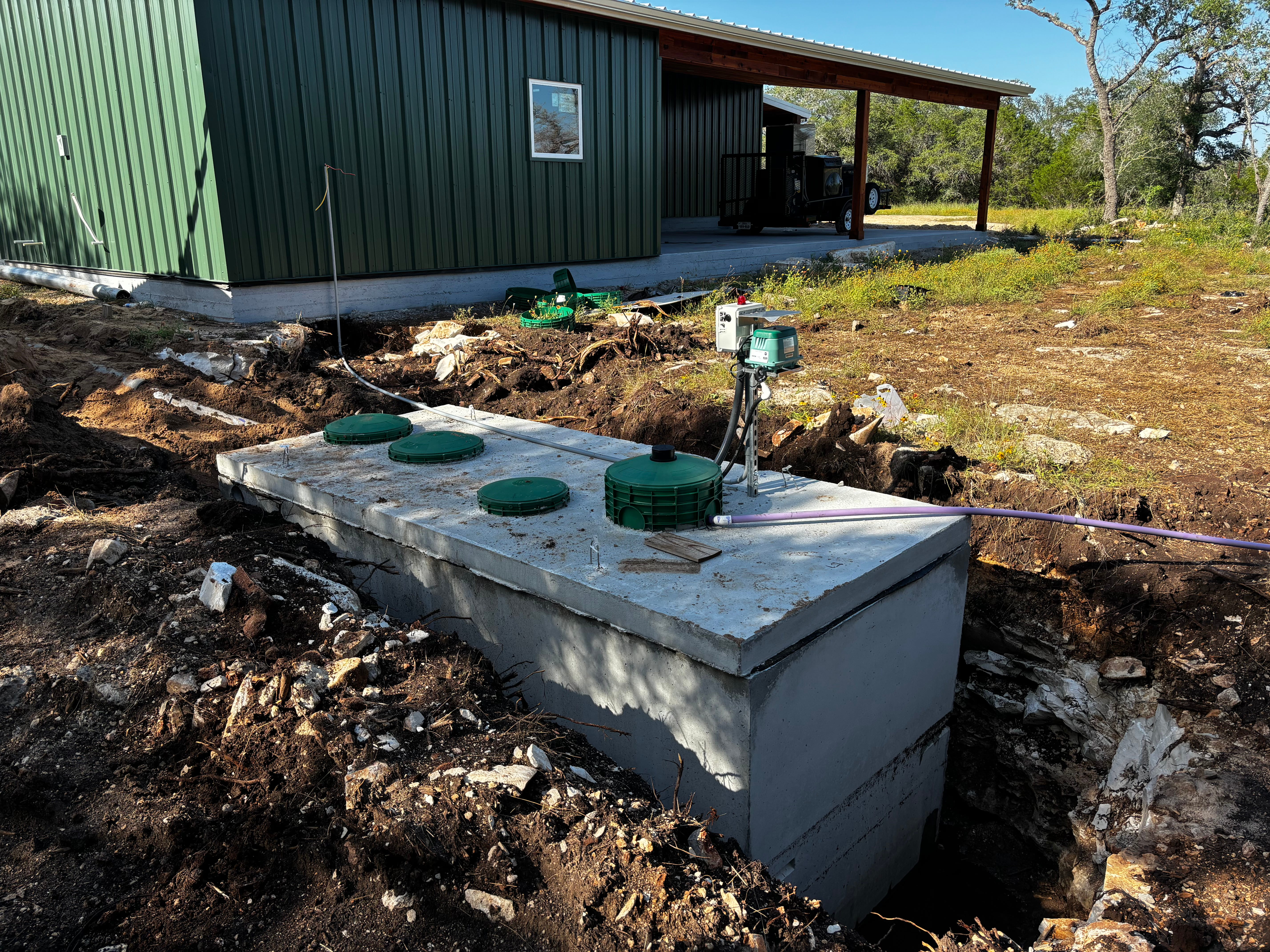 Excavator lifting concrete tank during excavation in Bastrop Texas