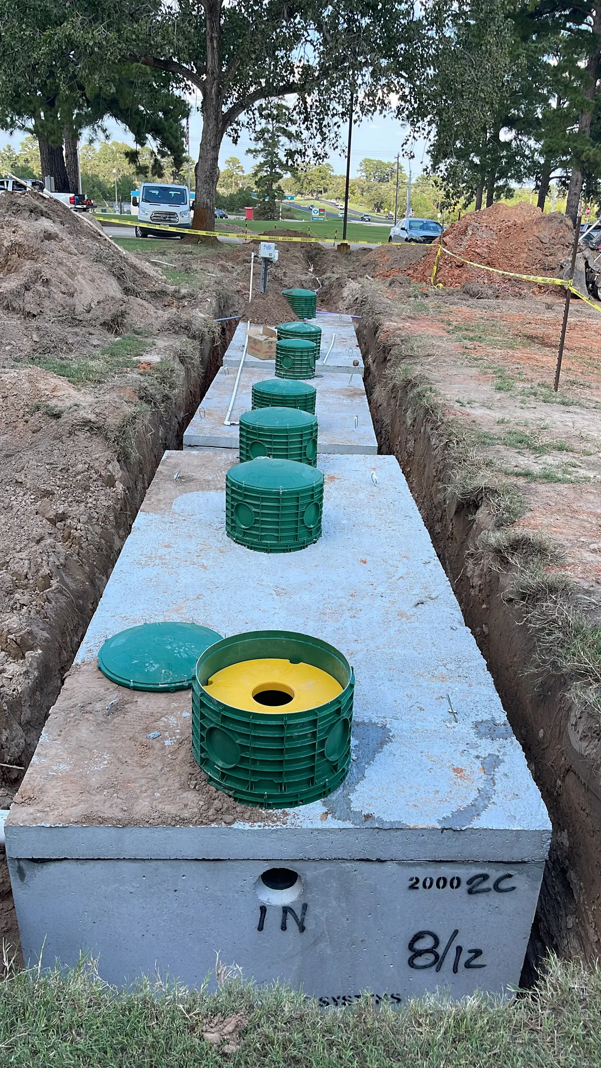 Excavator lifting concrete tank during excavation in Bastrop Texas