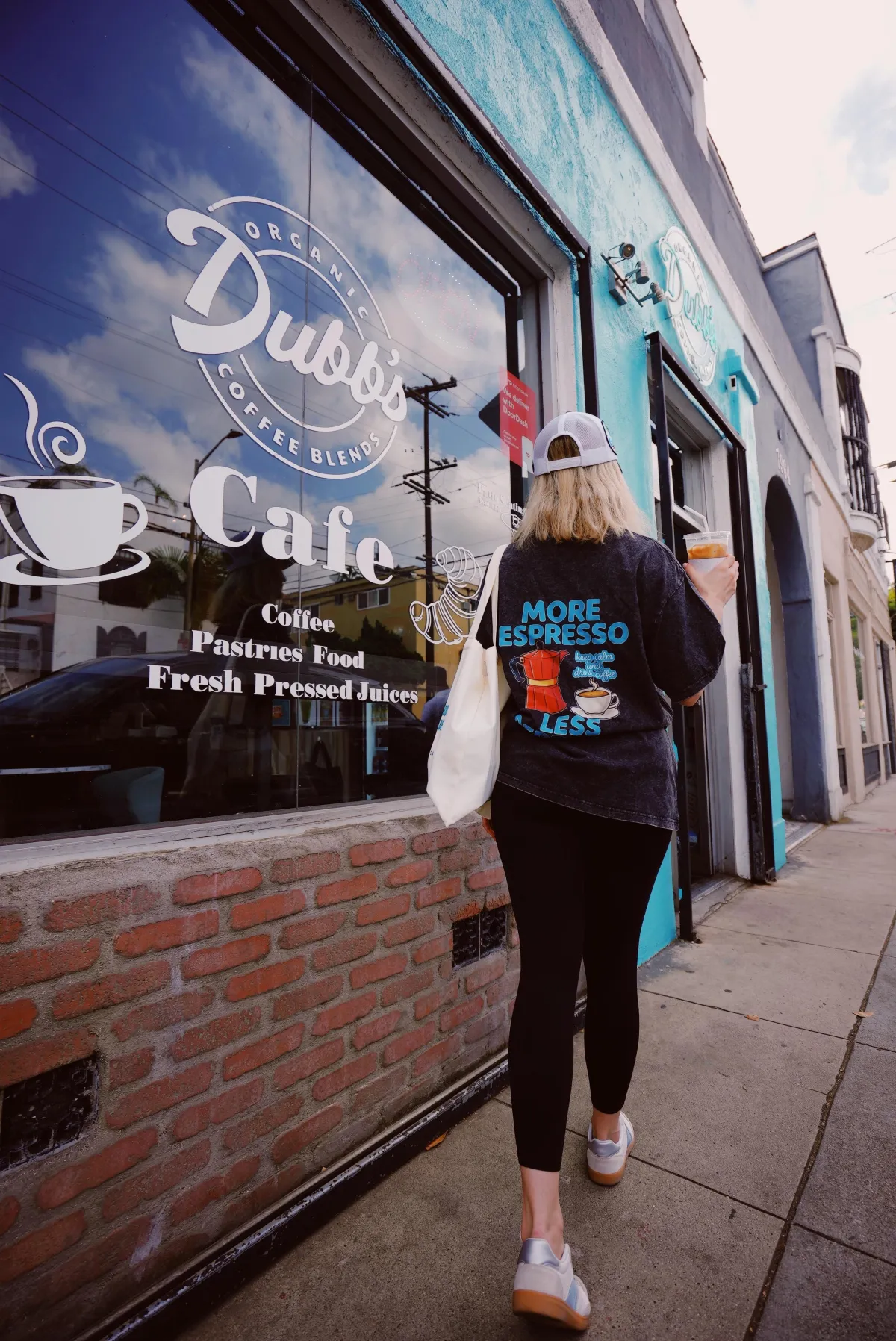 Customer wearing a "More Espresso Less Stress" shirt at Dubb's Organic Coffee storefront in West Hollywood
