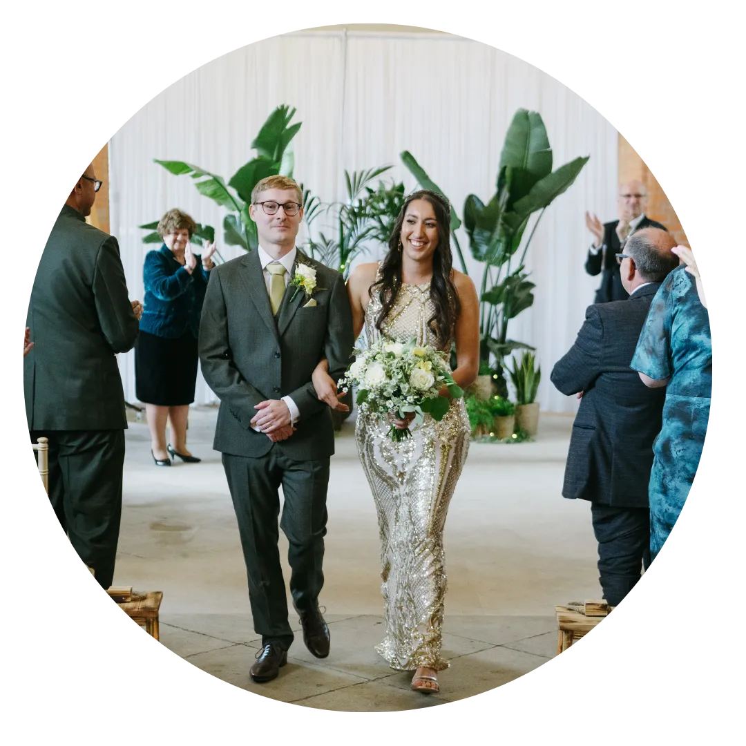 Couple walking down the aisle with plant backdrop