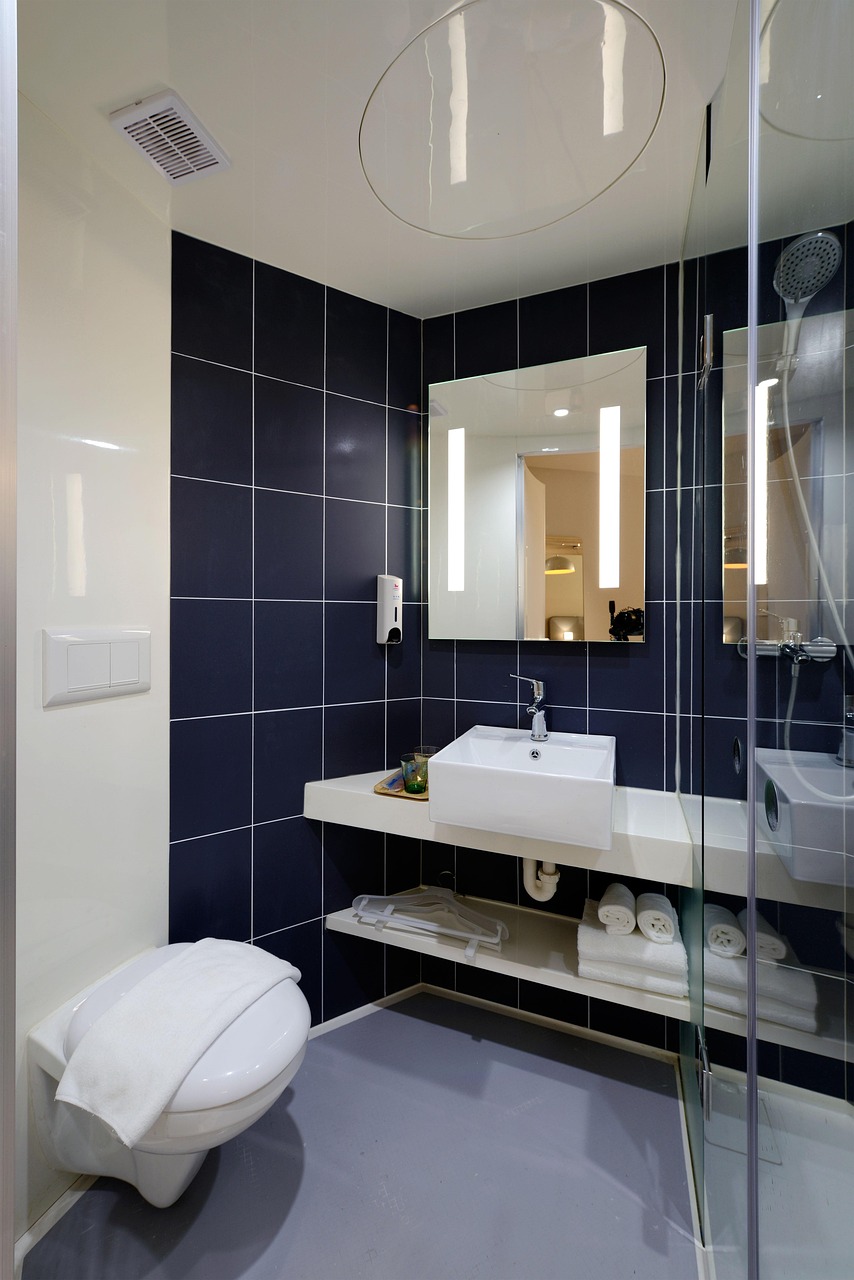 Modern remodeled bathroom with dark dual vanity, large mirror, and glass shower enclosure