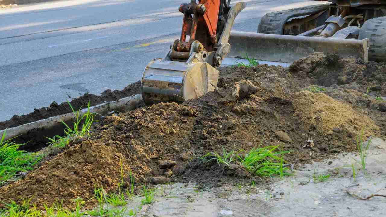 A bulldozer is digging a hole in the ground next to a road.