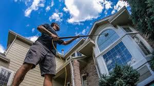 A person cleaning the windows of a two-story house