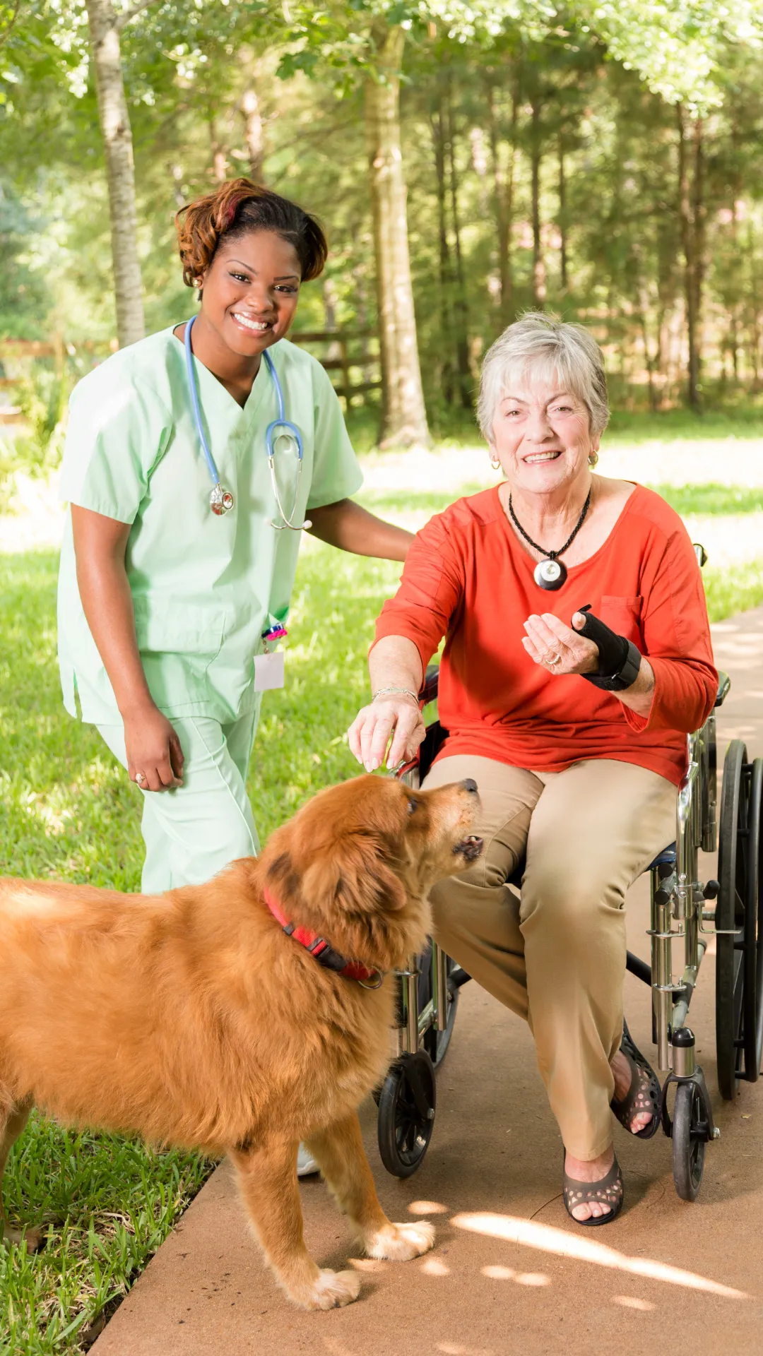 Nurse with elderly woman in wheelchair and therapy dog, outdoor care