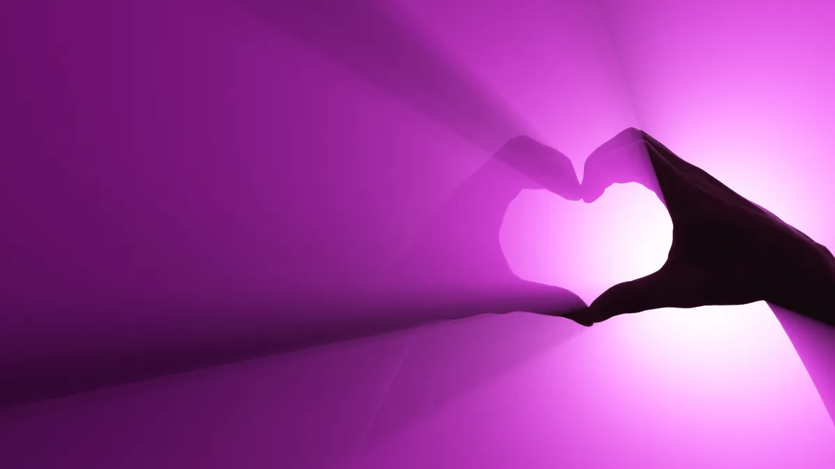 heart made with fingers on purple background