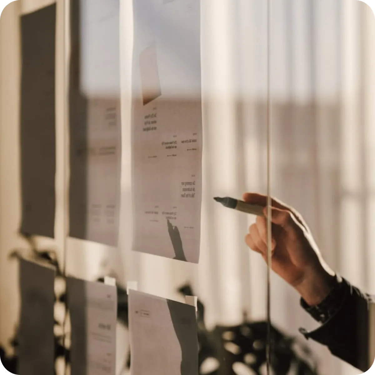 Close-up of a business consultant's hand reviewing strategic book planning documents and manuscript notes behind glass