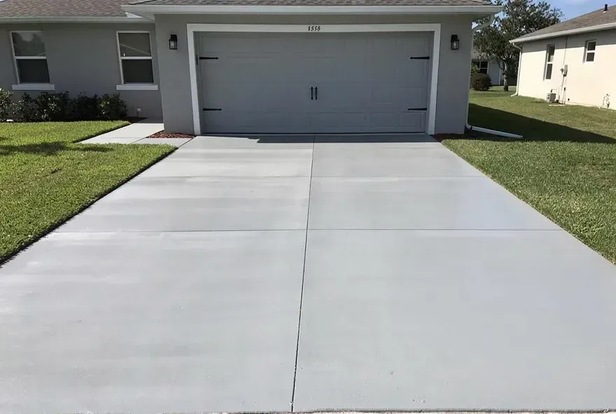 Freshly finished concrete driveway attached to a garage door on a residential property in Lake City, Florida