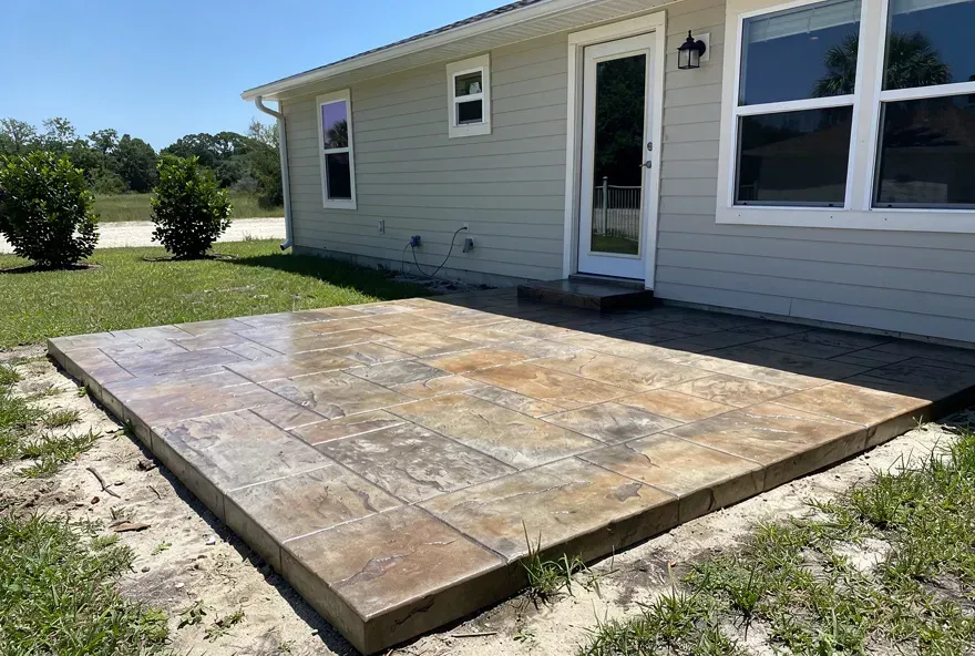 Settled stamped concrete patio with stone pattern attached to a home in Lake City, Florida