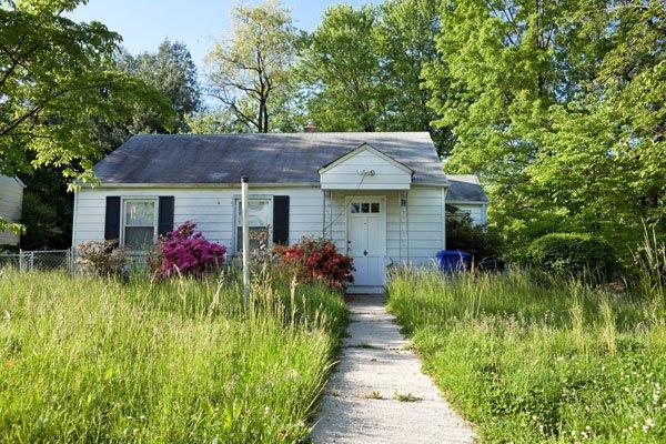 small distressed white house with an old gray roof