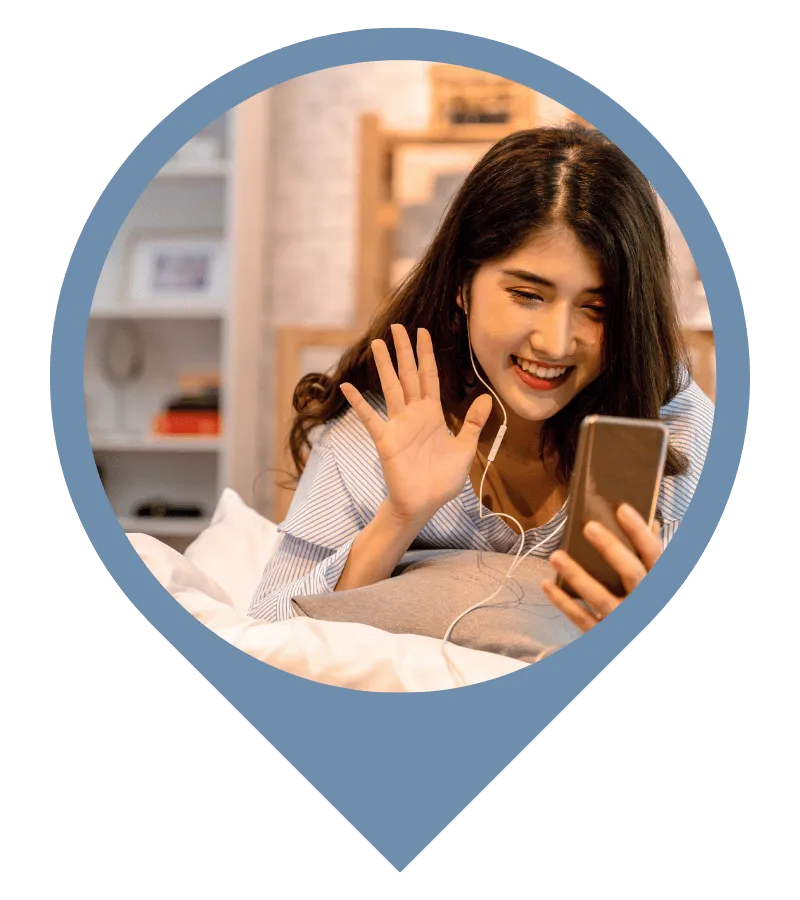 girl on dorm bed waving at phone