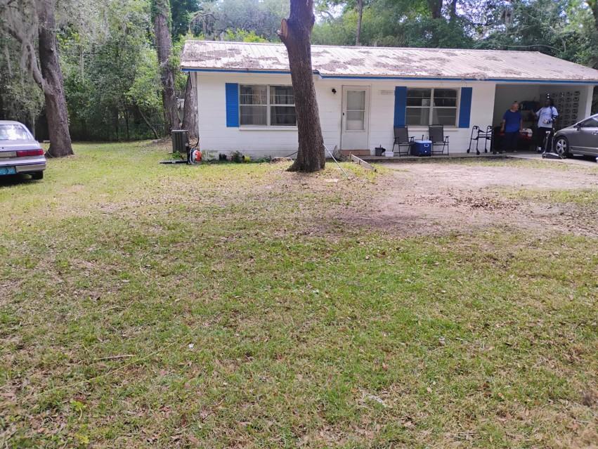Another view of a freshly mowed front yard showing a trimmed walkway and trees