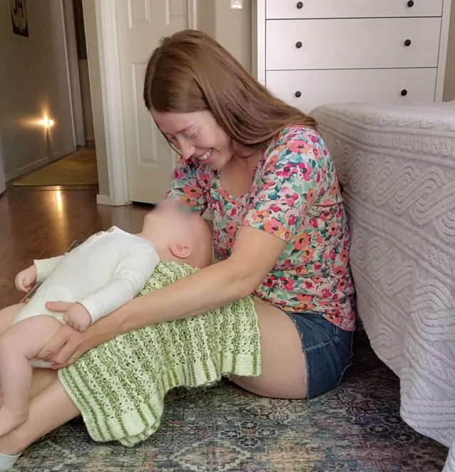 Baby lying down receiving back support or massage from hands out of frame