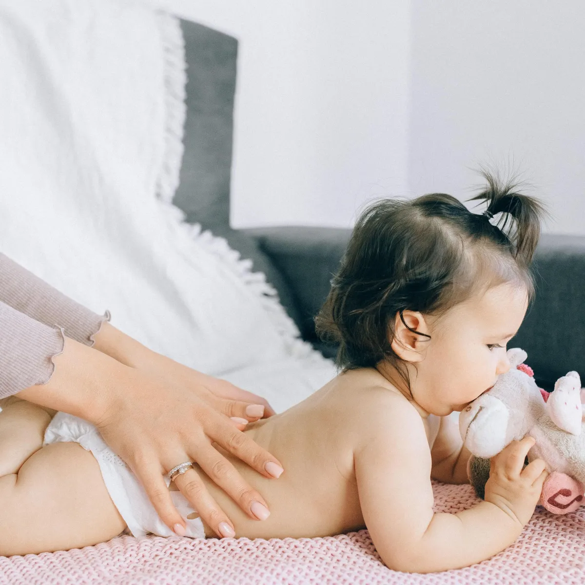 Baby lying down receiving back support or massage from hands out of frame