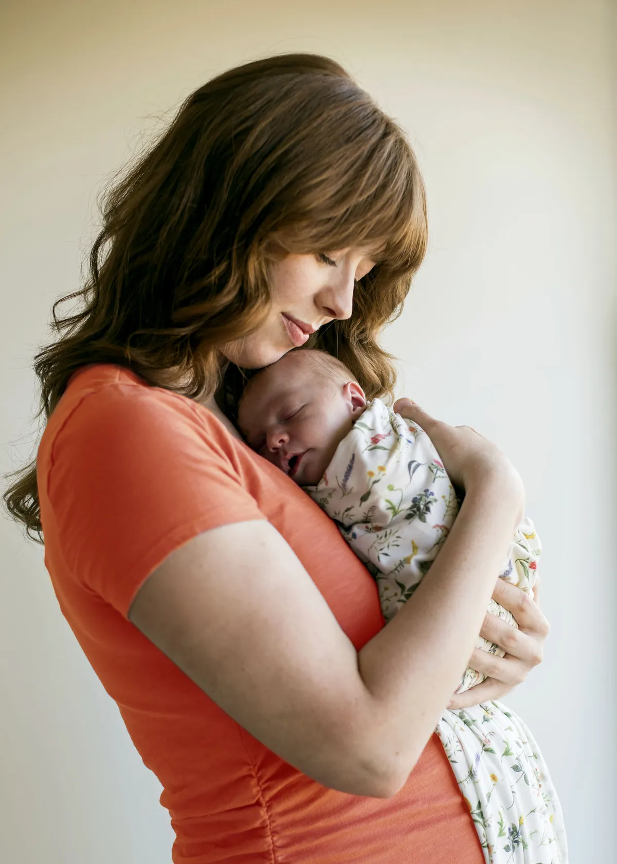 Mother holding newborn baby in orange top