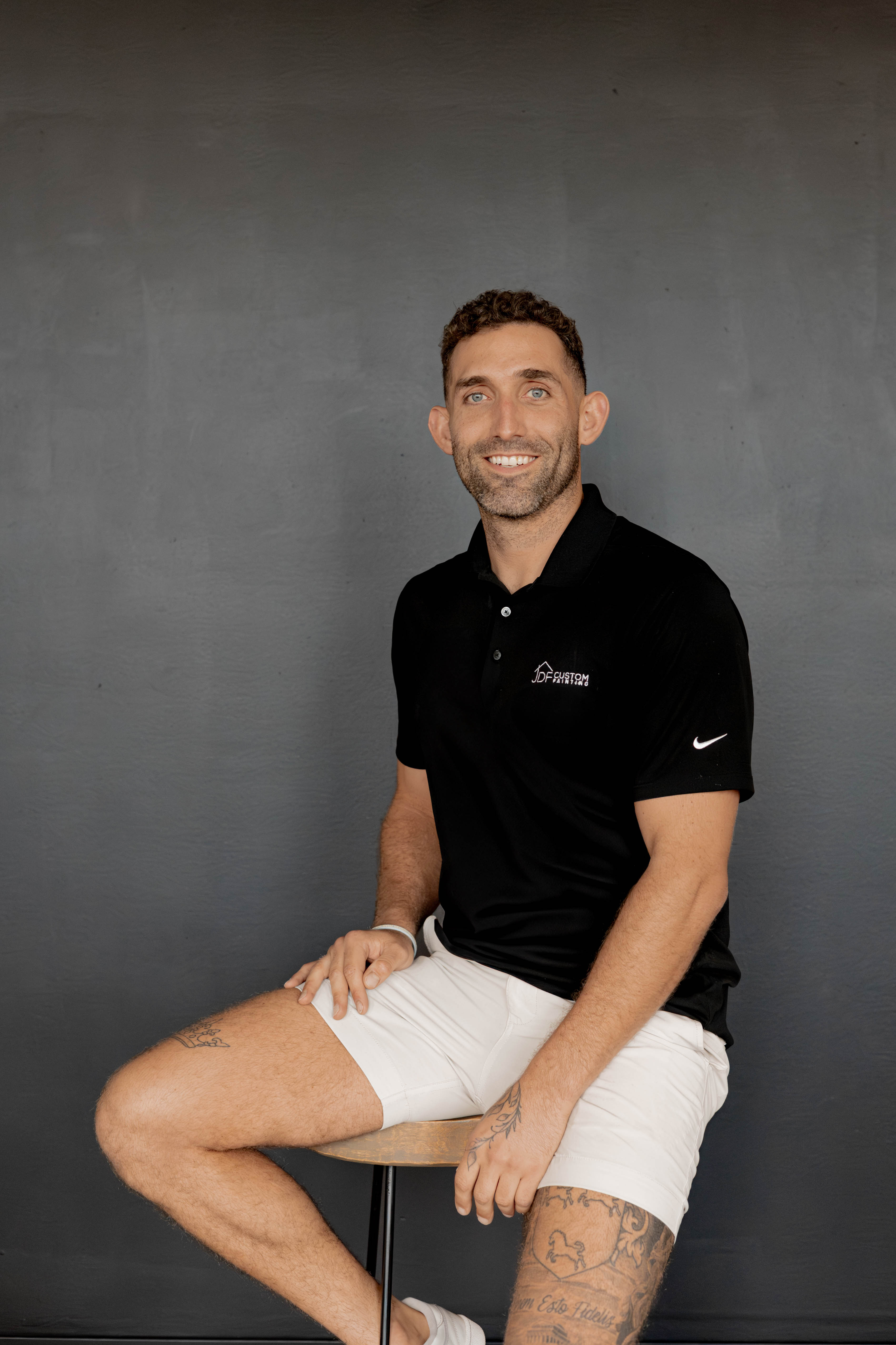 A behind-the-scenes view of two painters, one male and one female, preparing brushes and mixing paint in a sunlit studio. The workspace is filled with color swatches, sketches, and paint cans. Their expressions show focus and camaraderie, capturing the authentic spirit and teamwork of the company.
